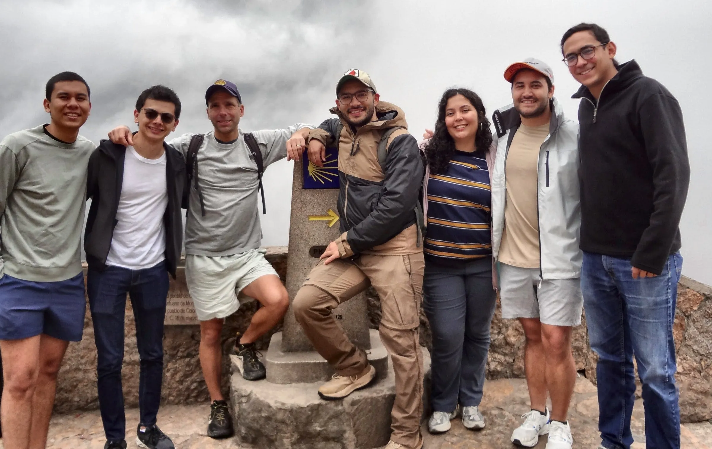 Ocho integrantes del equipo de Fronte posan juntos al aire libre en la cima de una montaña, en un día nublado.